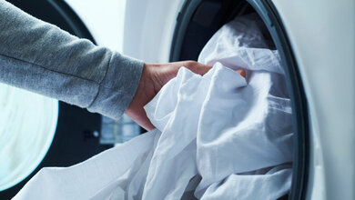 Ein Mann steckt Wäsche in die Waschmaschine