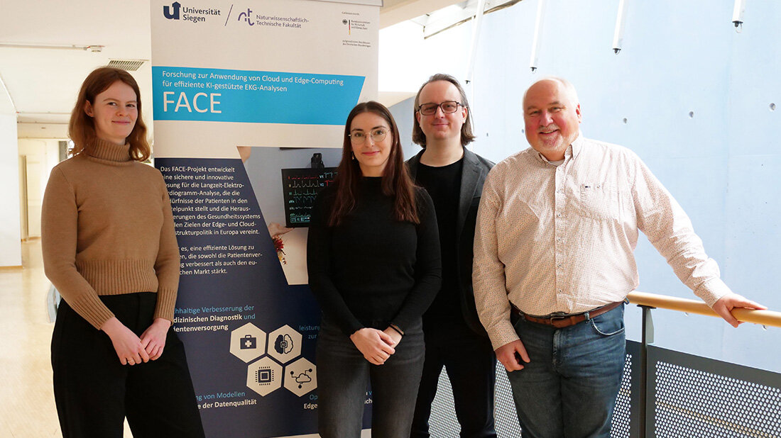 Zwei Frauen und zwei Männer vor einem Aufsteller mit unleserlicher Aufschrift, heller Hintergrund