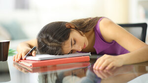 Foto einer über ihre Notizen gebeugt schlafenden Frau