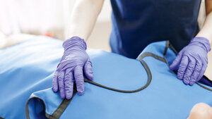 Foto, auf dem zwei Hände in medizinischen Handschuhen zu sehen sind