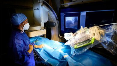 Dr. Julia Wagenpfeil, Oberärztin der Klinik für Diagnostische und Interventionelle Radiologie des UKB, schafft den Gefäßzugang für den Eingriff und bereitet den Roboter vor.