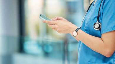 Mobiltelefone im Krankenhaus Foto einer Person in Medizinerkleidung bei der Bedienung eines Smartphones
