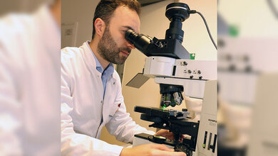 Forscher im weißen Kittel am Mikroskop