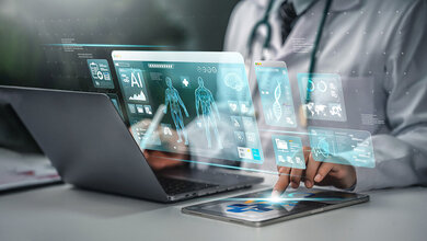 Person am Laptop, vor dem grafisch Elemente dargestellt sind, um künstliche Intelligenz zu suggerieren.