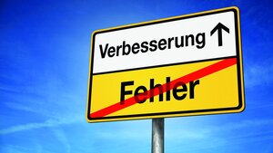 Ortausgangsschild mit mit den Begriffen „Fehler“ (durchgestrichen) und „Verbesserung“ (als nächster„Ort“)