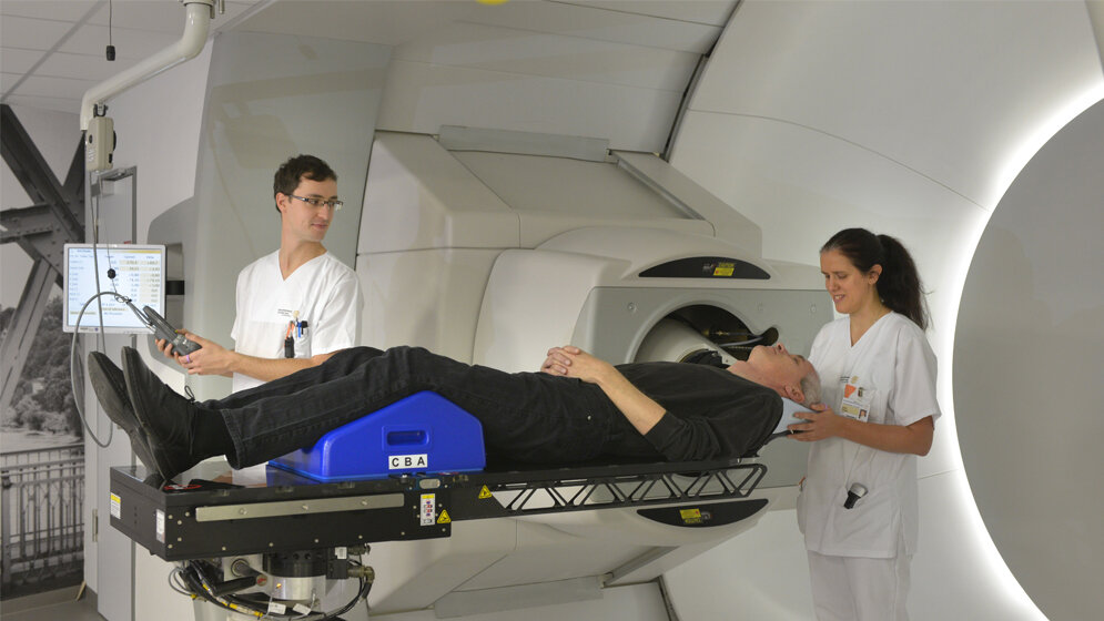 Zwei MTRA lagern am Behandlungsplatz der Universitäts ProtonenTherapie einen Patienten