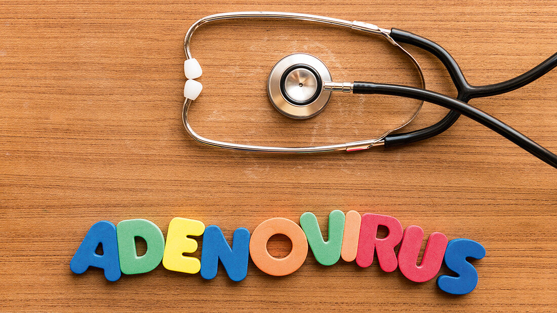 Foto mit Stethoskop und dem aus bunten Buchstaben gelegten Wort „Adenovirus“