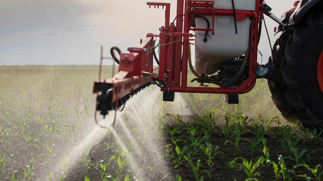 Ein Traktor sprüht Pestizide auf ein Feld   
