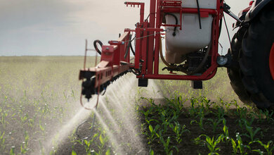 Ein Traktor sprüht Pestizide auf ein Feld   