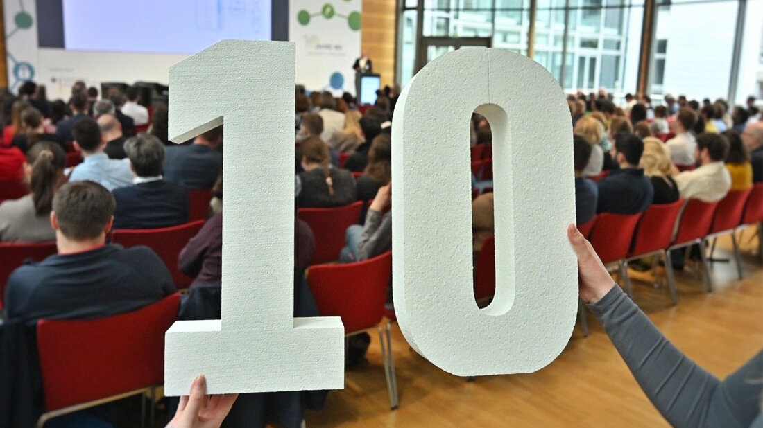 Jubilaeum.jpg Eine 10 wird in die Kamera gehalten.