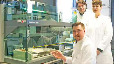Pipettierroboter_im_Life_Brain_Forschungszentrum_Dr_Andreas_Forstner_sitzend_vorne_PD_Dr_Rupert_Conrad_Psychologin_Stefanie_Rambau.jpg Am Pipettierroboter im Life & Brain Forschungszentrum