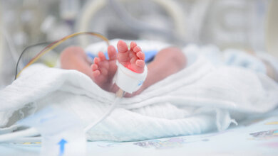 Füße eines Neugeborenen Babys zu sehen inmitten von Handtüchern in einem Brutkasten, Kabel zu sehen und am Fuß angebrachte Messung der Sauerstoffsättigung