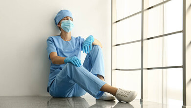 Medizinisches Personal sitzt am Boden und ist erschöpft