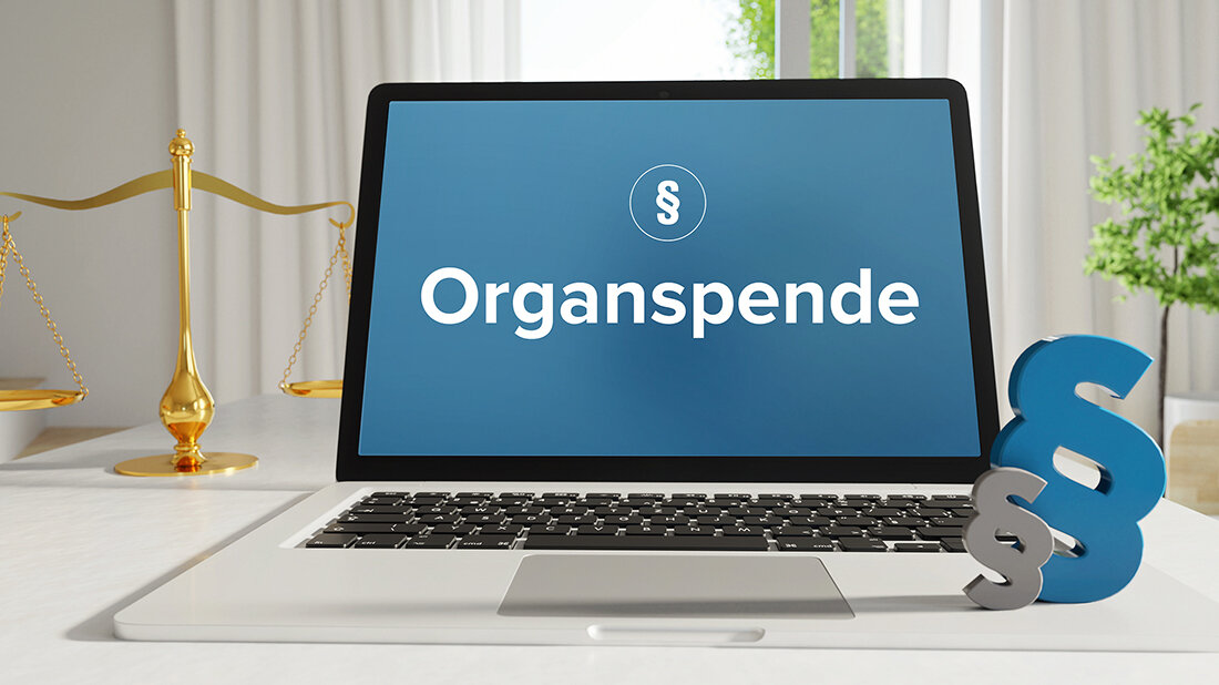 Abbildung eines Laptops, auf dessen Bildschirm das Wort „Organspende“ und das Paragrafenzeichen zu sehen sind