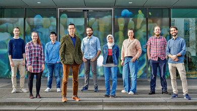 Gruppenfoto von 9 Forschenden vor einem Gebäude.