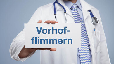 Ein Arzt hält ein Schild mit dem Aufdruck Vorhofflimmern.