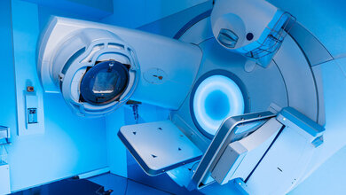 Gerät für Strahlentherapie in einem blau beleuchteten Raum.