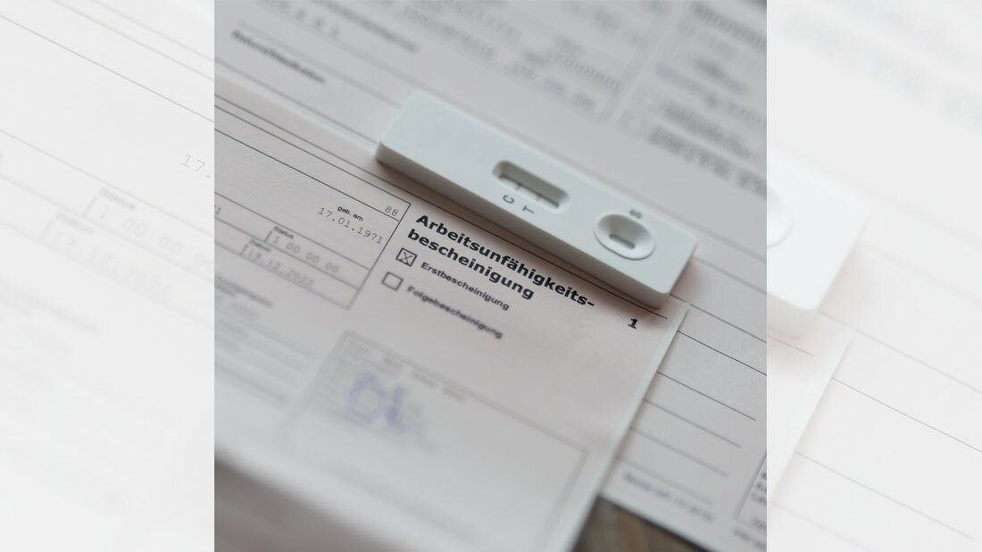 Arbeitsunfaehigkeit_01.jpg Positiver Coronatest, der auf einer Arbeitsunfähigkeitsbescheinigung liegt.