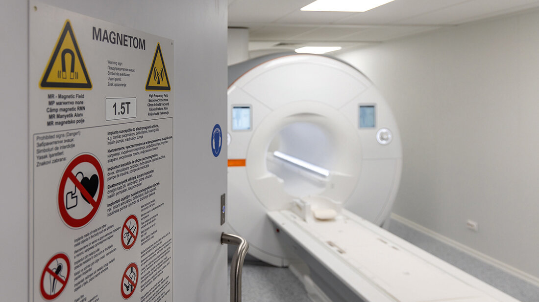 Foto mit Blick durch eine geöffnete Tür mit Sicherheitshinweisen auf ein Magnetom