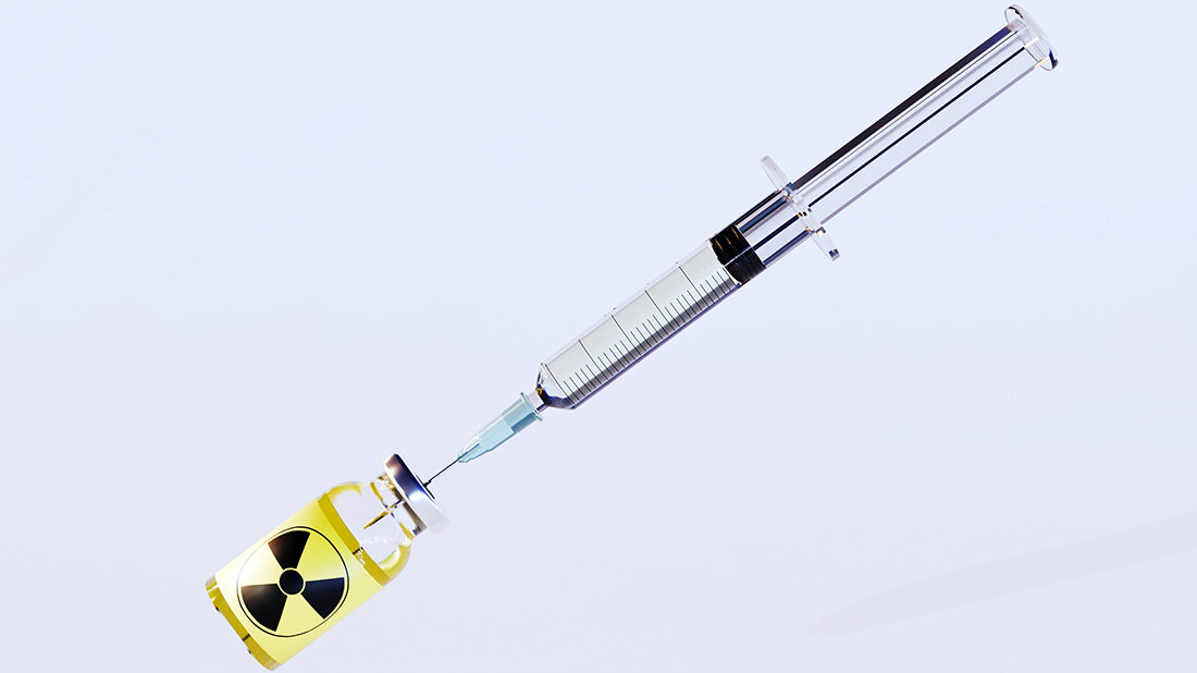 Radiopharmaka.jpg Spritze sticht in Medikamentenfläschchen mit radioaktivem Logo, auf weißem Hintergrund