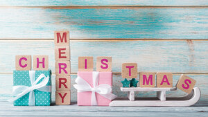 Arrangement mit Weihnachtsutensilien und Holzwürfeln, auf denen „Merry Christmas“ zu lesen ist