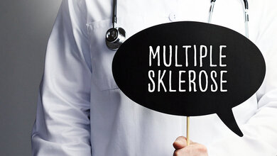 Eine Person in Medizinerkleidung und mit Stethoskop hält ein Schild in der Form einer Sprechblase vor sich, auf dem „Multiple Sklerose“ steht.