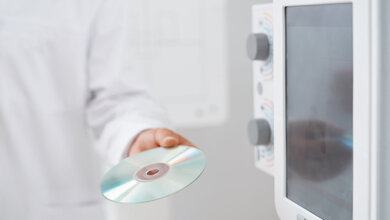 Arzt überreicht in der Radiologie eine CD mit Daten.