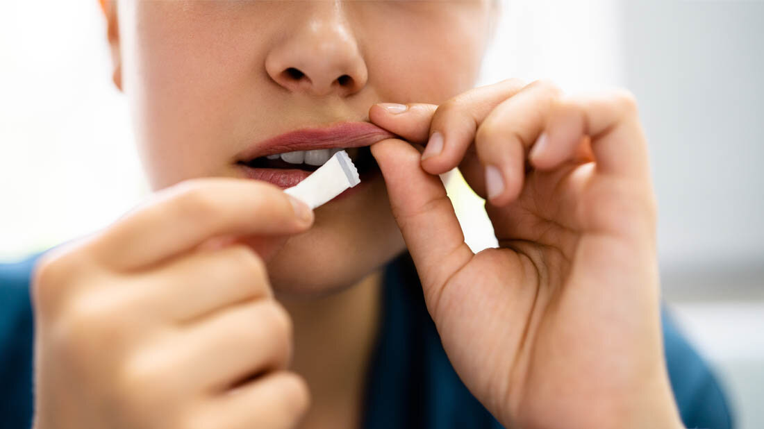 Junge Frau, die sich einen Nikotinbeutel hinter der Lippe platziert.
