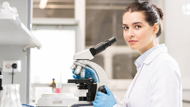 Foto einer Labormitarbeiterin an einem Mikroskop