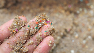 Foto einer Hand mit einer Mischung aus Sand und Mikroplastik