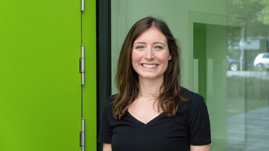 Frau vor einer Glastür, links grüner Hintergrund