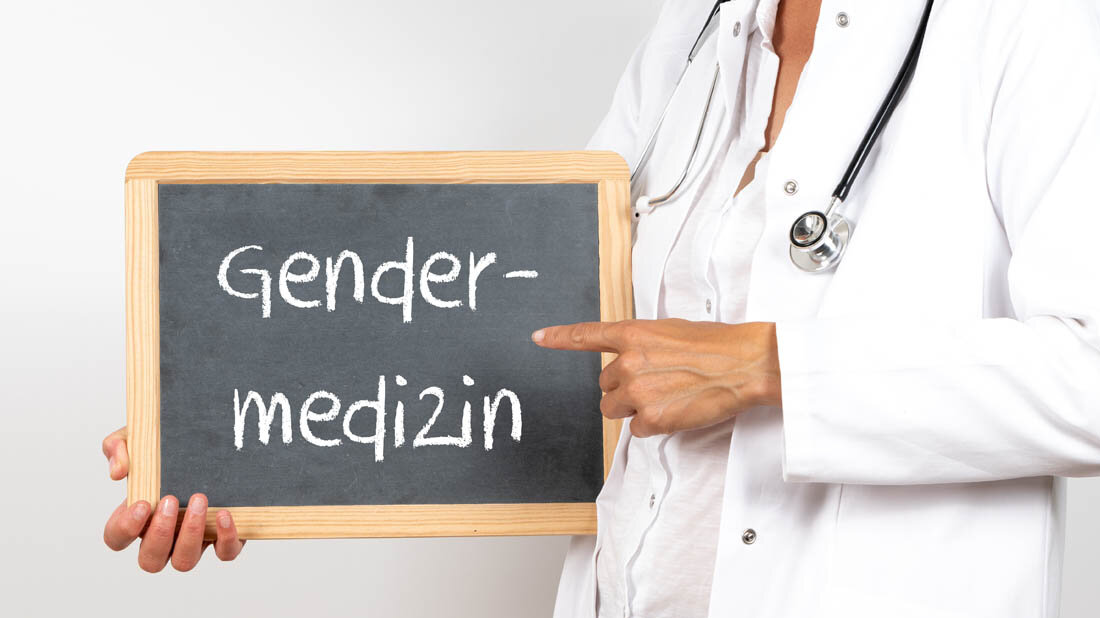 Ärztin mit einer Tafel, auf der Gendermedizin steht.