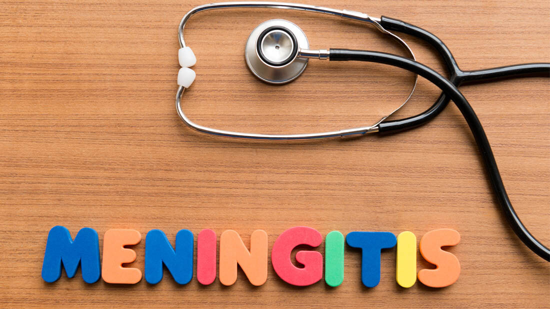 Buchstaben, die das Wort Meningitis bilden und ein Stethoskop auf einem Tisch.