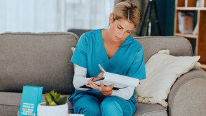 Foto einer schreibenden Frau in Arztkleidung