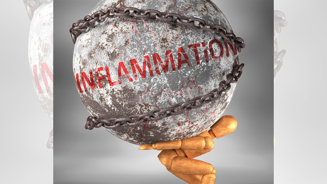 Eine Figur aus Holz trägt eine Steinkugel mit der Aufschrift Inflammation.