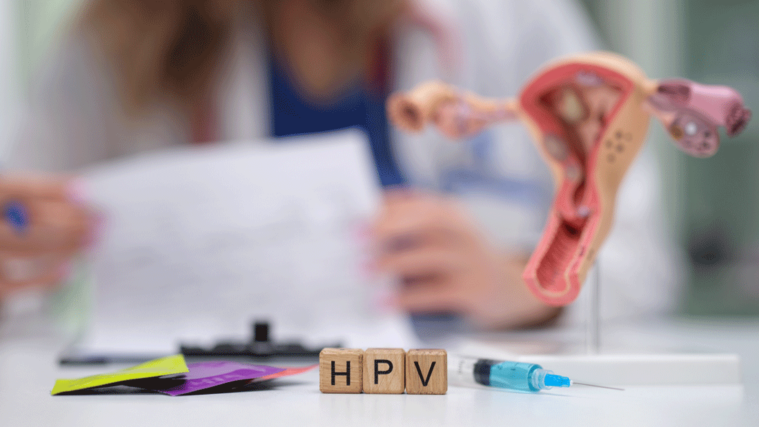 AdobeStock_1201169273.gif Im Vordergrund stehen Holzbuchstaben „HPV“ neben einer Spritze und einem Modell der weiblichen Geschlechtsorgane. Im Hintergrund liest medizinisches Personal Unterlagen.