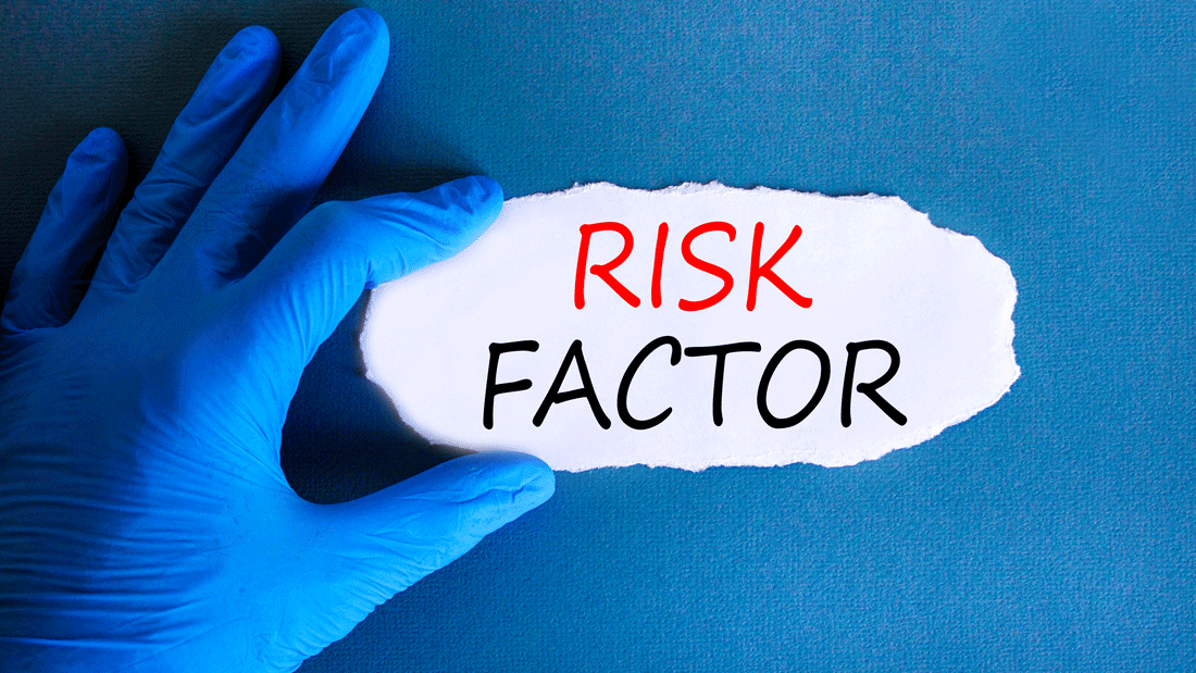 Blaue behandschuhte Hand zieht Papier auf und legt den Schriftzug „RISK FACTOR“ frei.