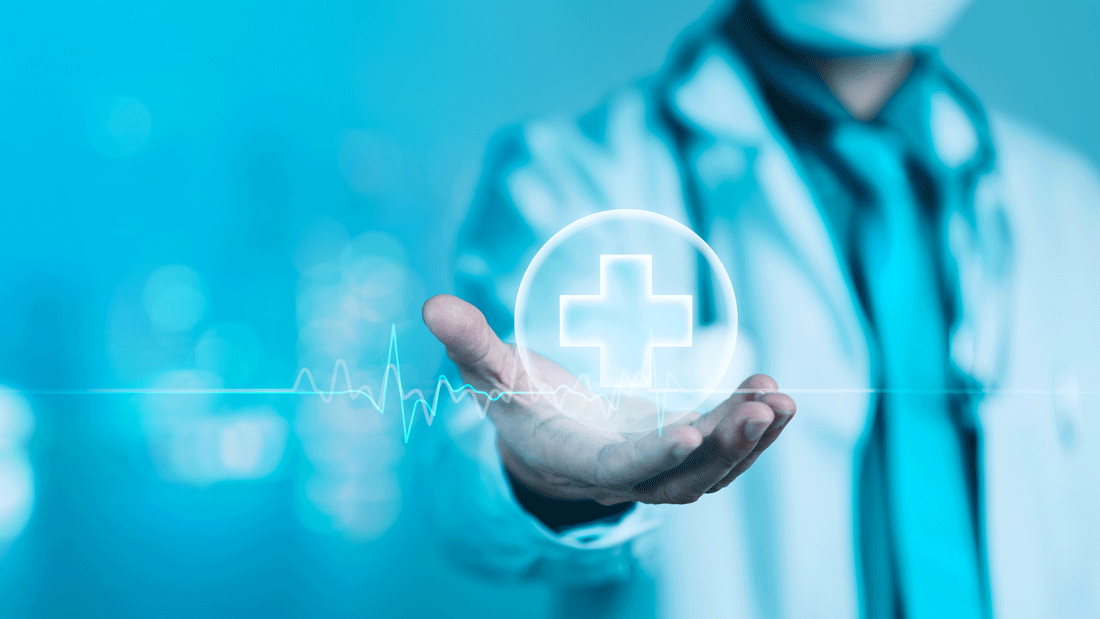 Das Bild zeigt eine Hand, die ein holografisches Symbol mit einem Kreuz und einer Herzfrequenzlinie hält.