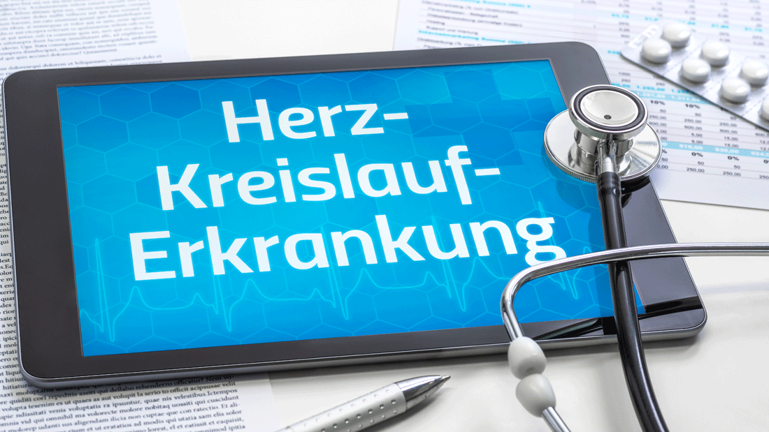 Tablet mit Schriftzug „Herz-Kreislauf-Erkrankung“, daneben Stethoskop, Tabletten und Unterlagen