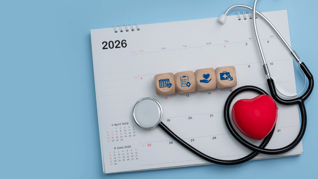 Dieses Bild zeigt einen Kalender mit dem Jahr 2026, zusammen mit medizinischen Gegenständen wie einem Stethoskop, einem roten Herz und Holzblöcken mit medizinischen Symbolen. 