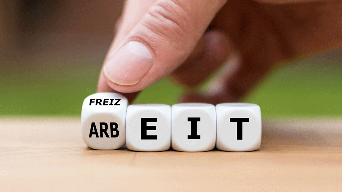  Das Bild zeigt Würfel, die die Wörter "Arbeit" und "Freizeit" darstellen. Eine Hand dreht einen Würfel, sodass die Kombination zwischen "Arbeit" und "Freizeit" verändert wird.