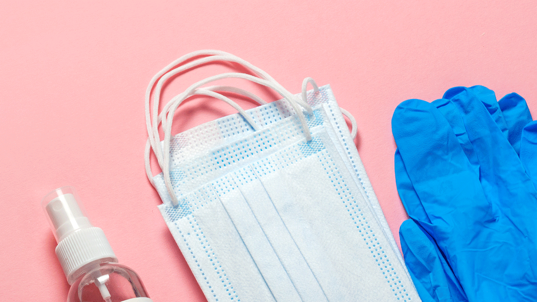 AdobeStock_387947852.gif Dieses Bild zeigt blaue chirurgische Masken, blaue Handschuhe und eine Sprühflasche, die auf einem rosa Hintergrund platziert sind.