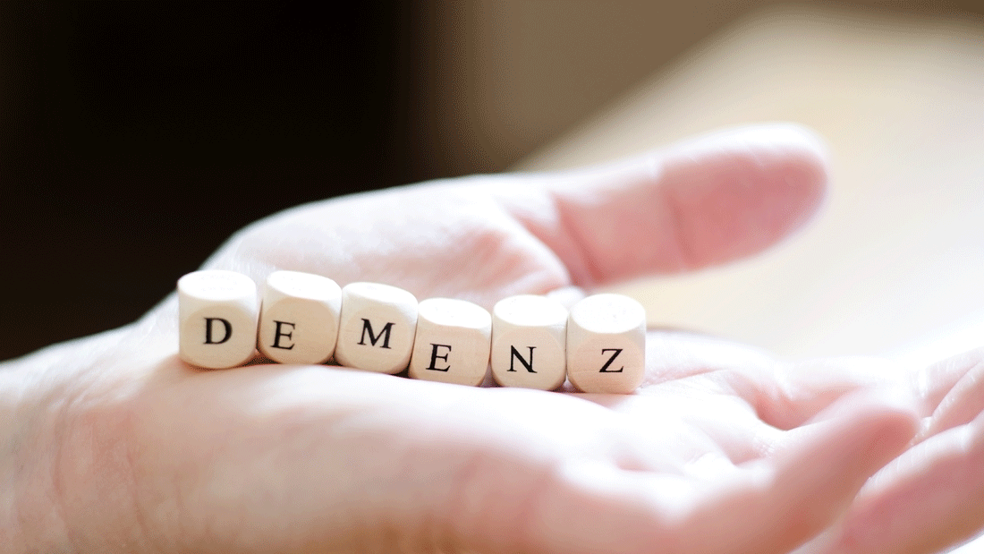 Dieses Bild zeigt eine Hand, die Holzblöcke mit der Aufschrift „DEMENZ" hält.