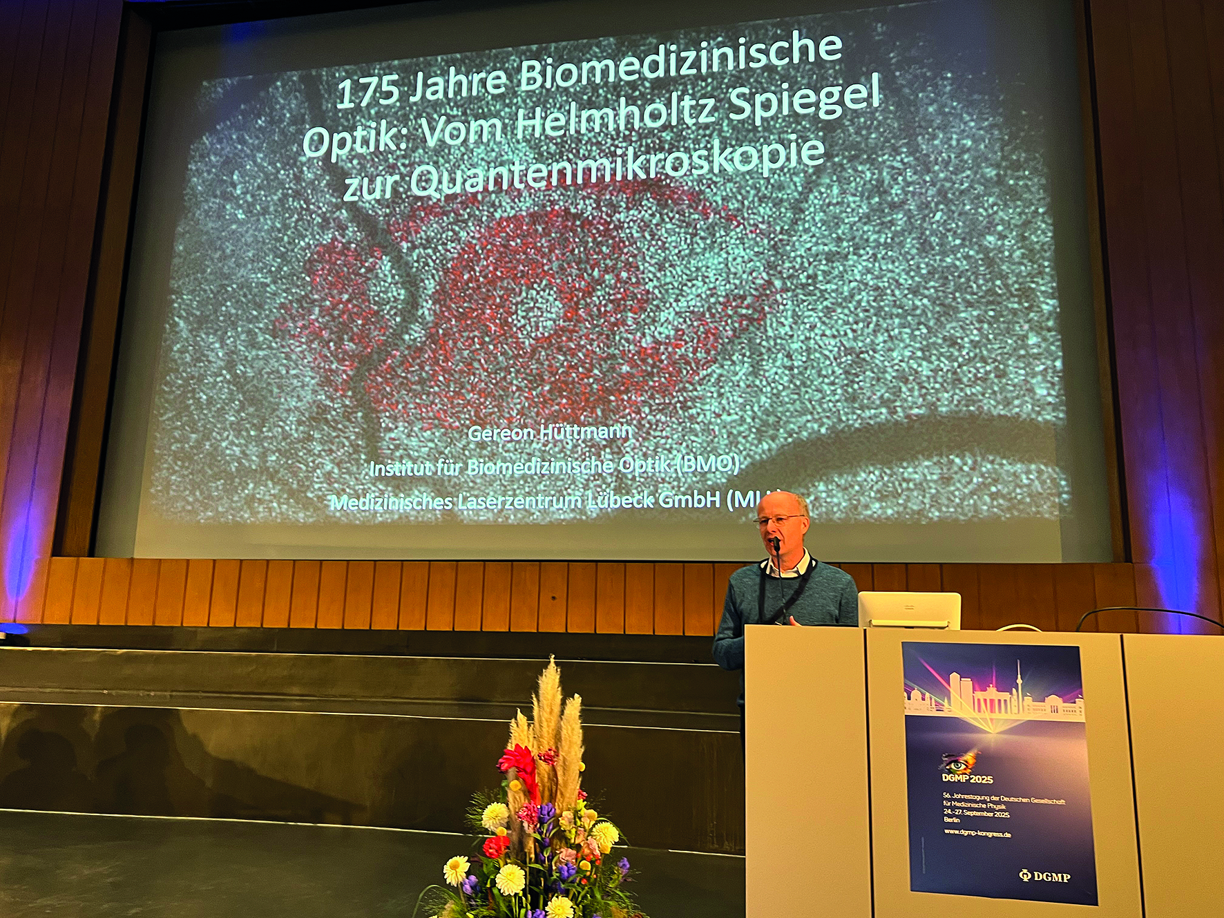 Foto des Podiums mit Vortragendem und großem Display 