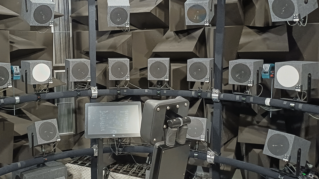 Dieses Bild zeigt einen schalltoten Raum (Anechoic Chamber), der speziell dafür entwickelt wurde, Schallreflexionen vollständig zu absorbieren und externe Geräusche zu isolieren. Die Anordnung umfasst mehrere Lautsprecher, die kreisförmig angeordnet sind. Die Wände sind mit schallabsorbierenden Materialien ausgestattet, um Echo und Störungen zu minimieren.