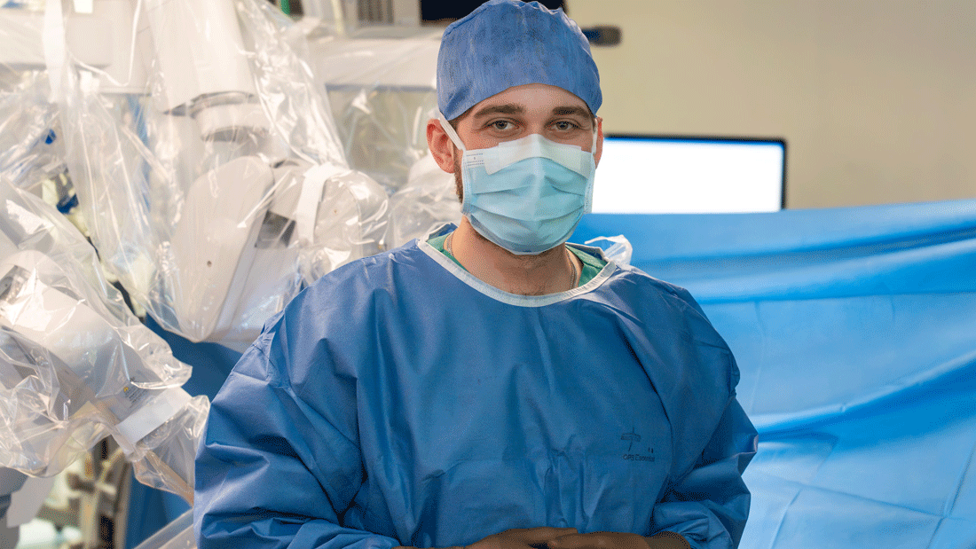 Dr. Julius Kaemmel vor einem Operationsroboter der Klinik für Herz-, Thorax- und Gefäßchirurgie am DHZC