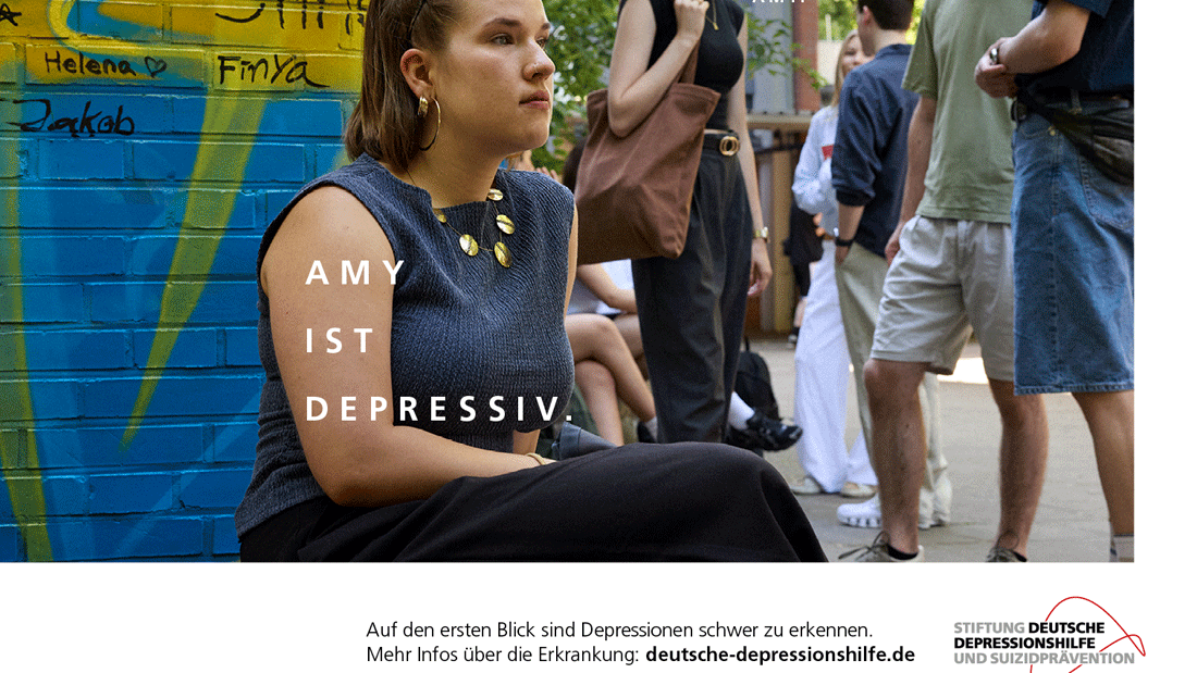 Eine junge Frau sitzt abseits vor einer bemalten Wand, während andere sich unterhalten. Text im Bild: „Amy ist depressiv“ – Hinweis auf oft unsichtbare Depressionen.